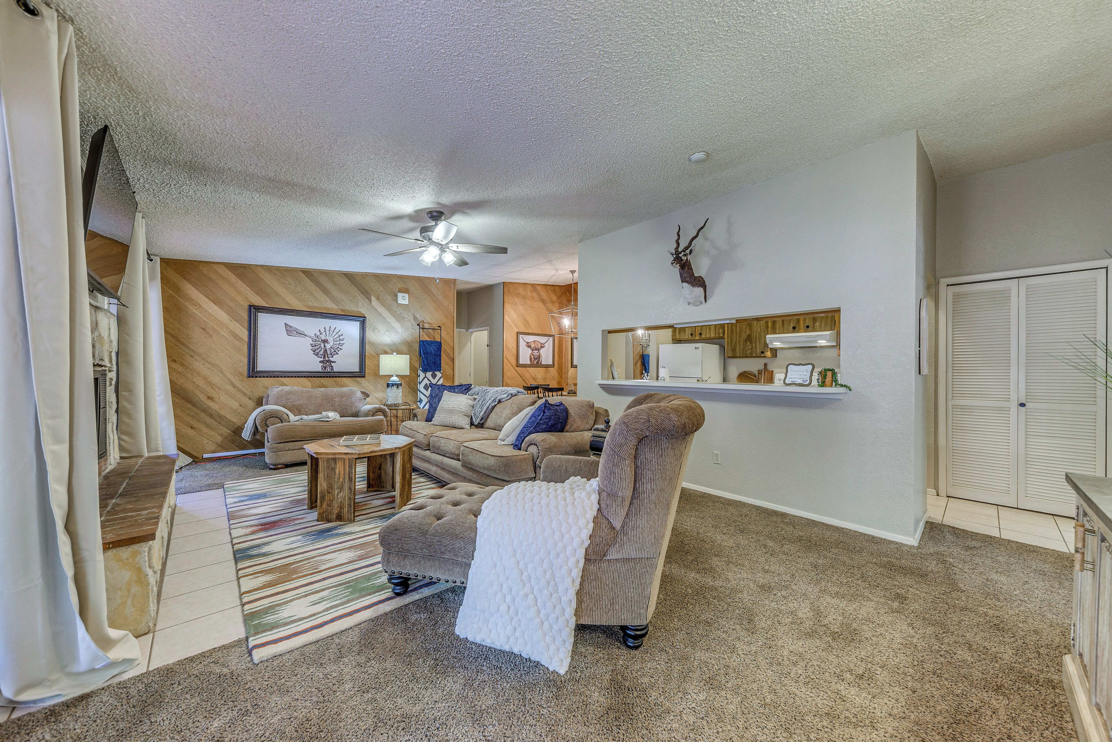 A living room with a sofa, armchair, ottoman, and a ceiling fan.