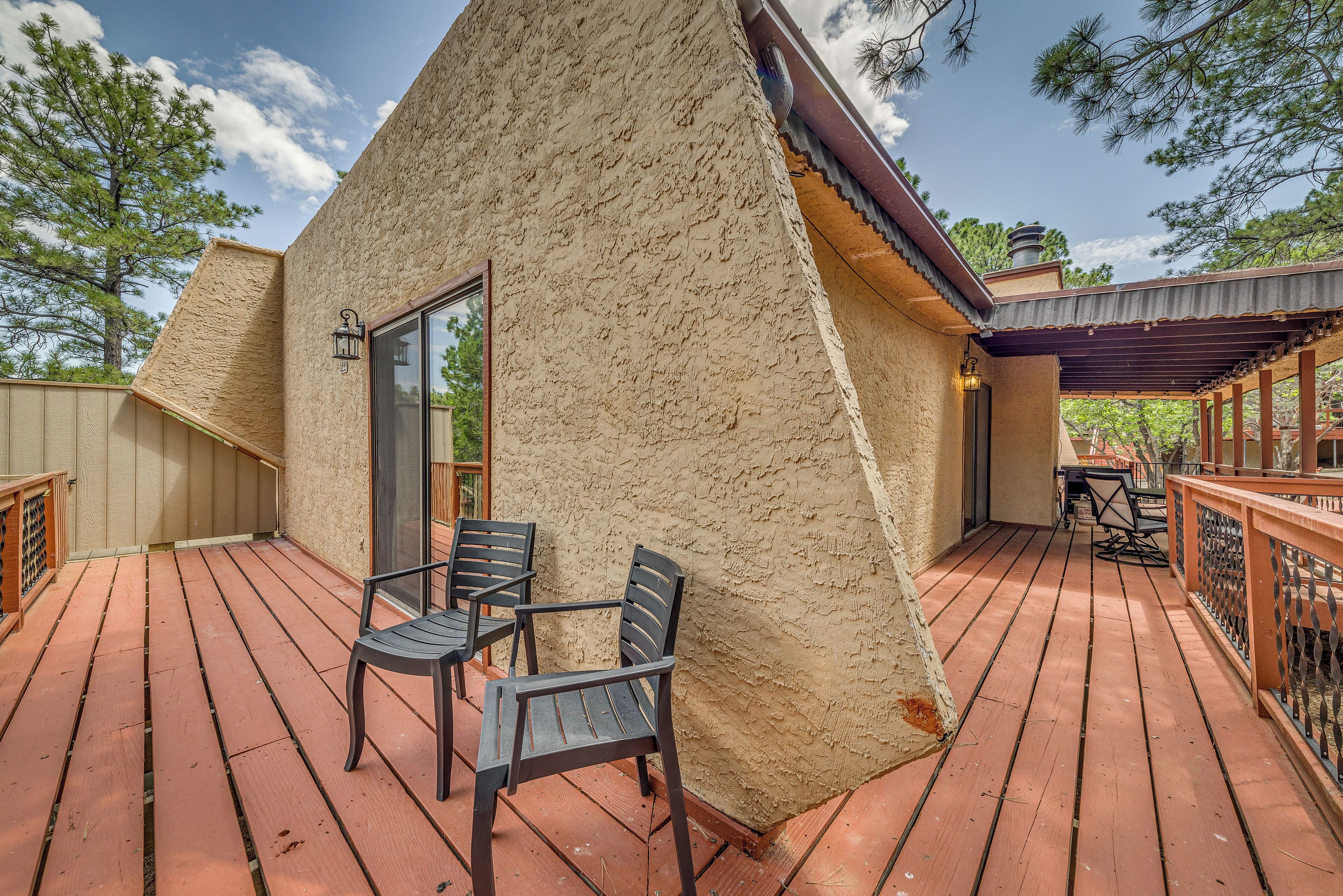 A cozy, triangular-shaped cabin with a wooden deck and outdoor seating area.