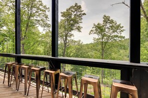 A deck with metal bar stools and a view of a forested area. - Cobbly Nob Resort Cabin: Hot Tub, Pool & Views! (Gatlinburg)