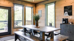 A wooden interior with a table and benches, large windows, and a coffee machine. - Cobbly Nob Resort Cabin: Hot Tub, Pool & Views! (Gatlinburg)