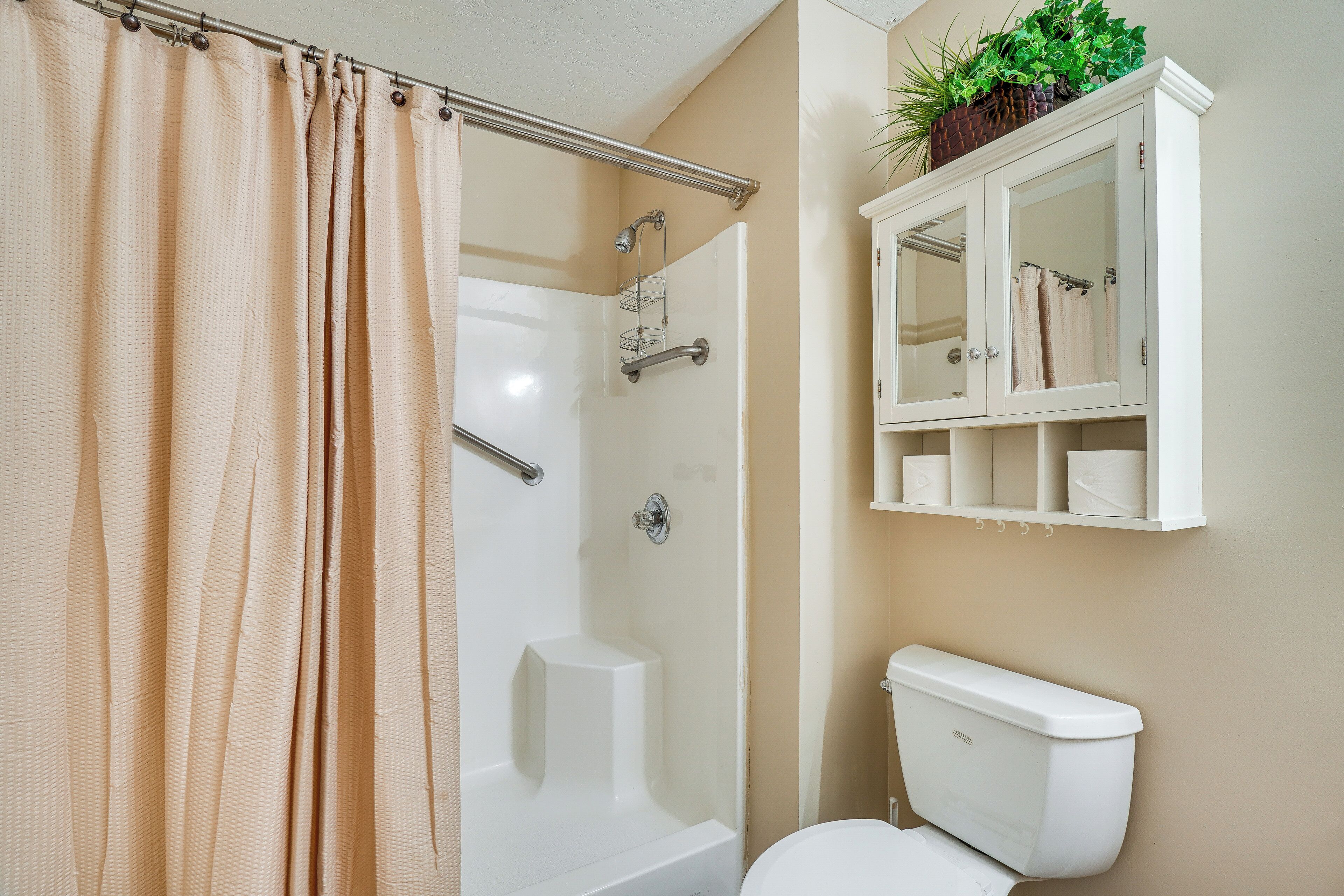 Een badkamer met douche, toilet en een kast met handdoeken.