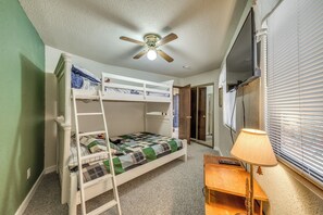 A bunk bed room with a ceiling fan, a desk, and a lamp. - Ruidoso Home w/ Balcony ~ 16 Mi to Ski Apache! (Ruidoso)