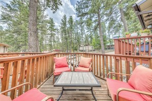 A wooden deck with a table and two chairs, surrounded by tall pine trees. - Ruidoso Home w/ Balcony ~ 16 Mi to Ski Apache! (Ruidoso)