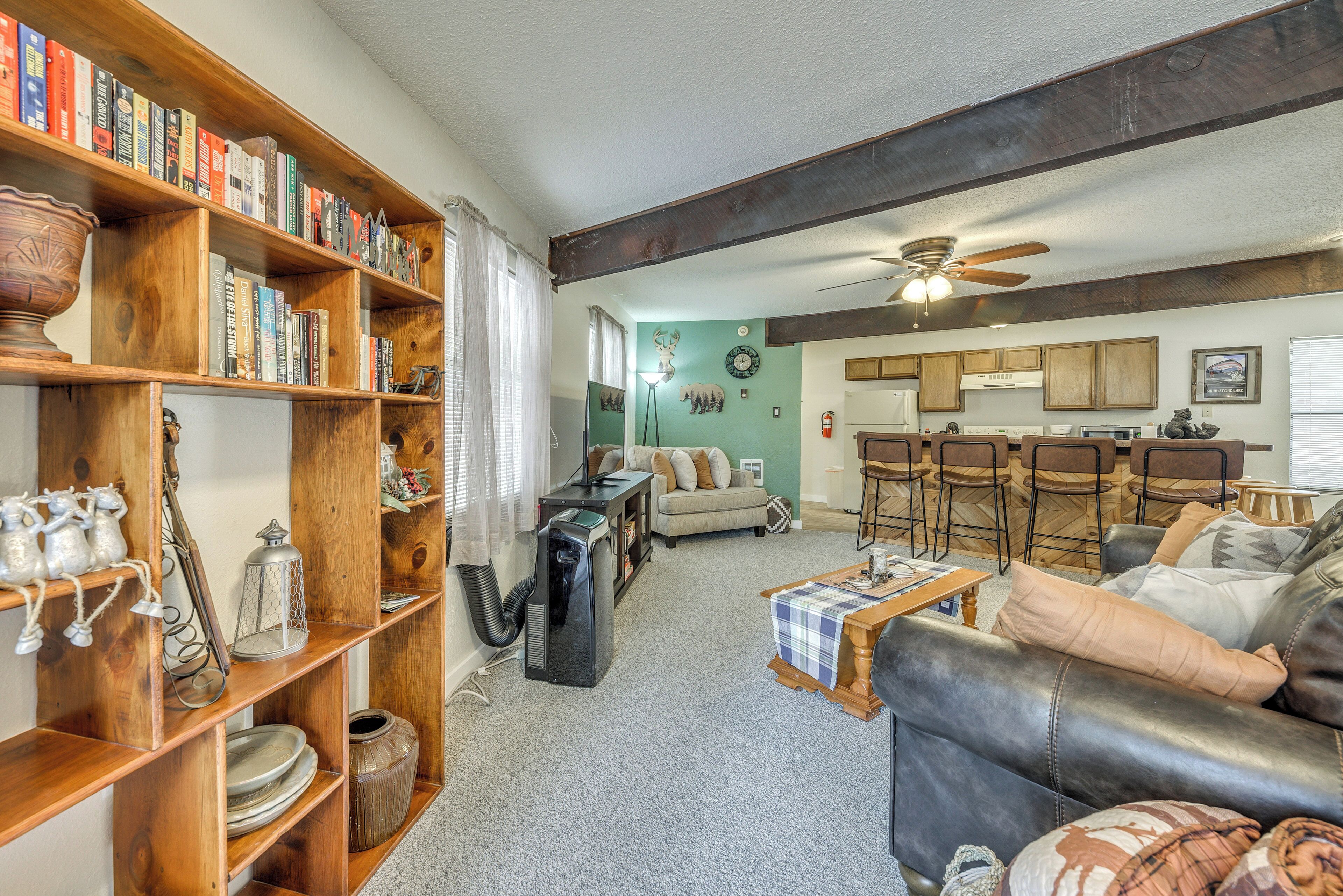 A cozy living room with a leather sofa, wooden bookshelves, and a dining area with a table and chairs.