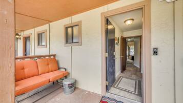 A hallway with a wooden bench, a door, and a small trash can.