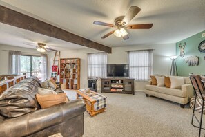 A living room with a leather sofa, a wooden coffee table, a television, and a bookshelf. - Ruidoso Home w/ Balcony ~ 16 Mi to Ski Apache! (Ruidoso)