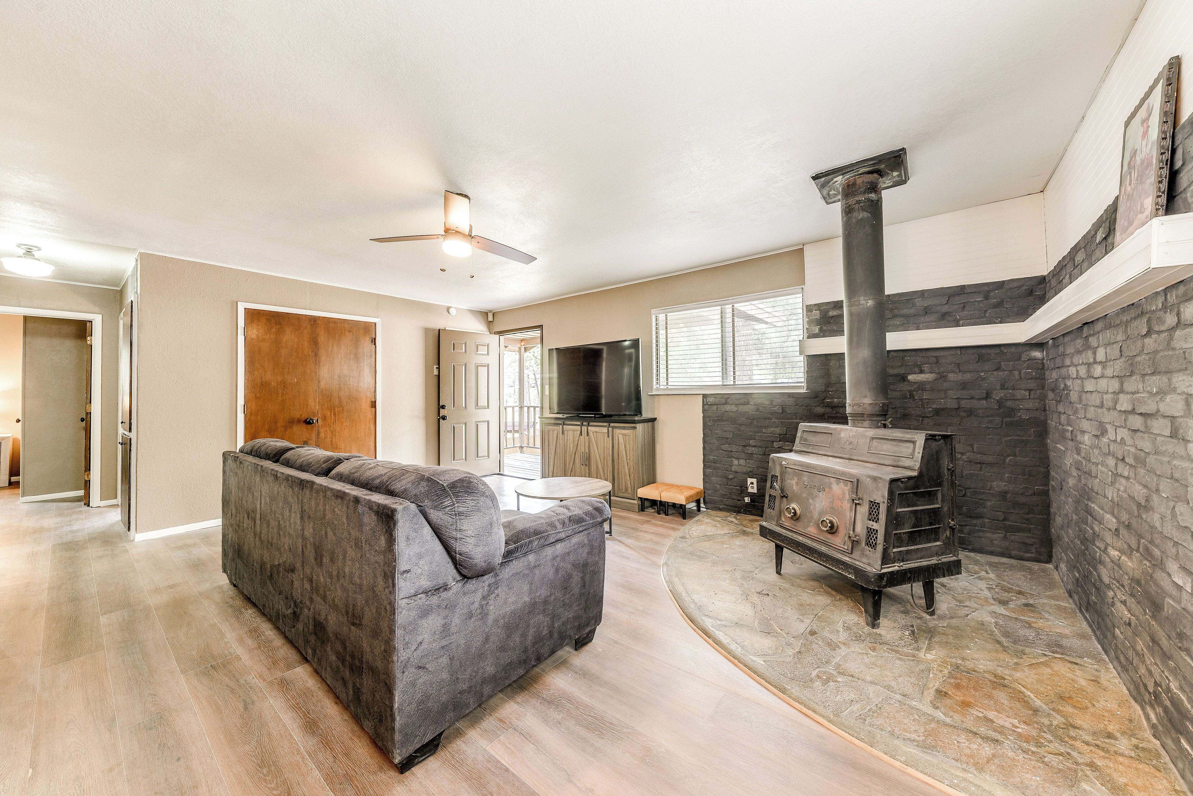 A modern living room with a gray sofa, a stone fireplace, and a television in the background.