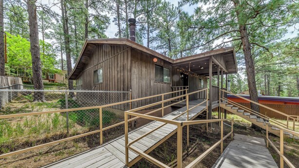 A wooden cabin with a covered porch and a wooden staircase leading to a deck. - Serene Ruidoso Cabin w/ Fenced Yard Near Downtown! (Ruidoso)
