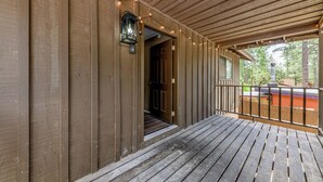 A wooden porch with a railing, a door leading to an interior, and string lights. - Serene Ruidoso Cabin w/ Fenced Yard Near Downtown! (Ruidoso)