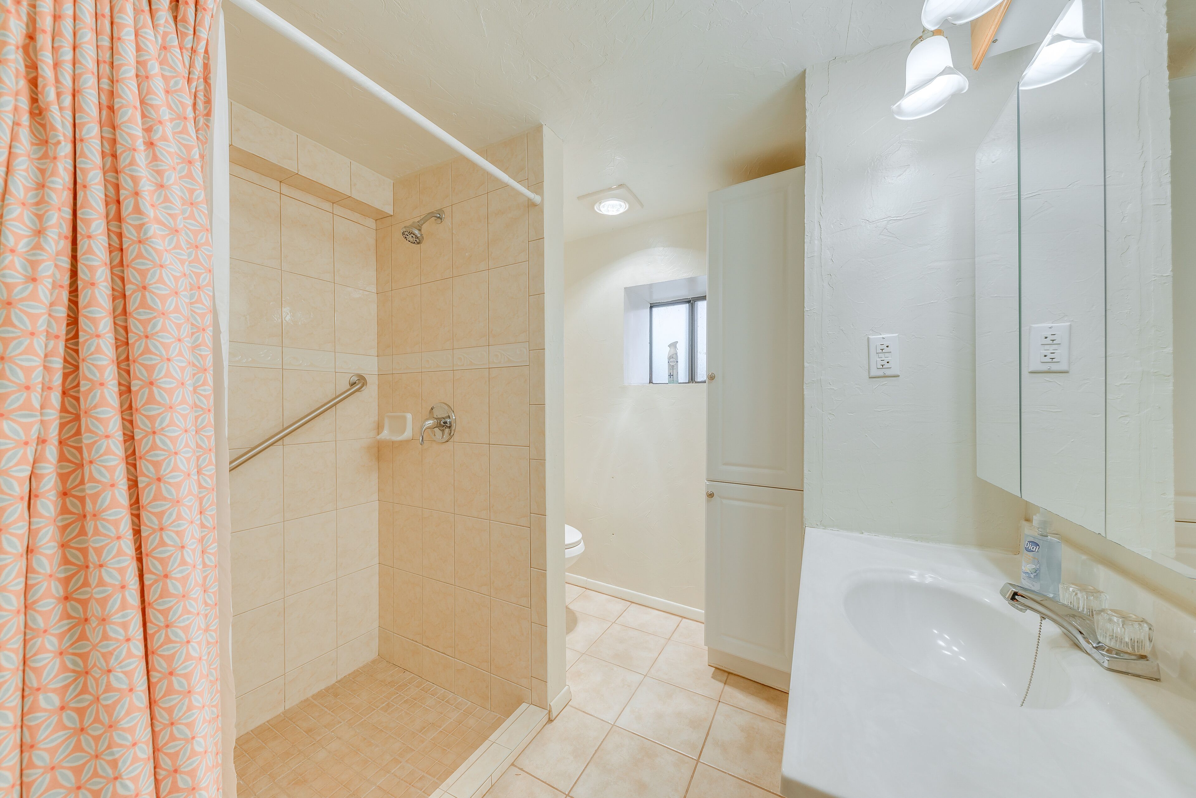 A bathroom with a shower, toilet, sink, and mirror.