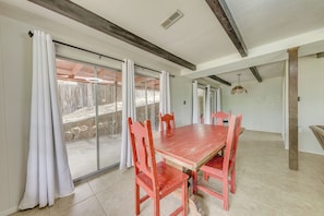 A dining area with a large table and chairs, a sliding glass door, and a ceiling with exposed beams. - Pet-friendly Ruidoso Escape w/ Spacious Deck! (Ruidoso)