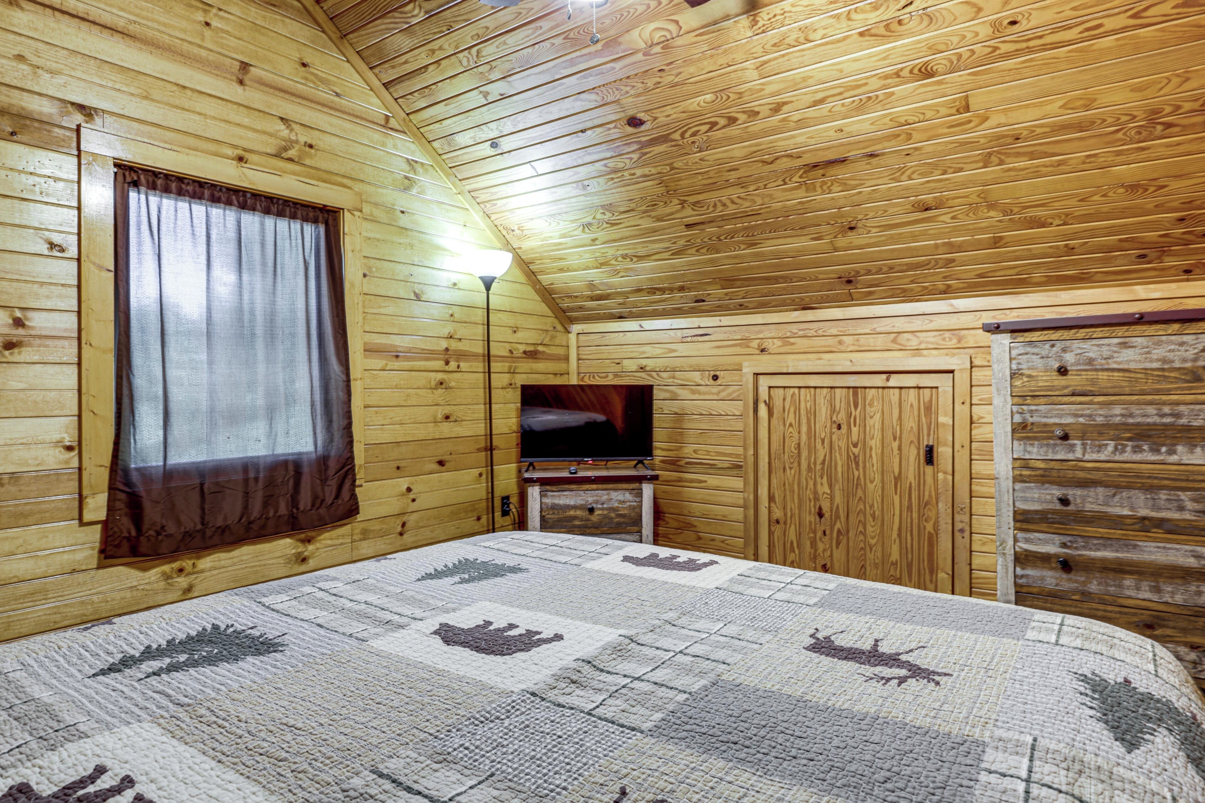 A wooden cabin room with a bed, a television, and a wardrobe.