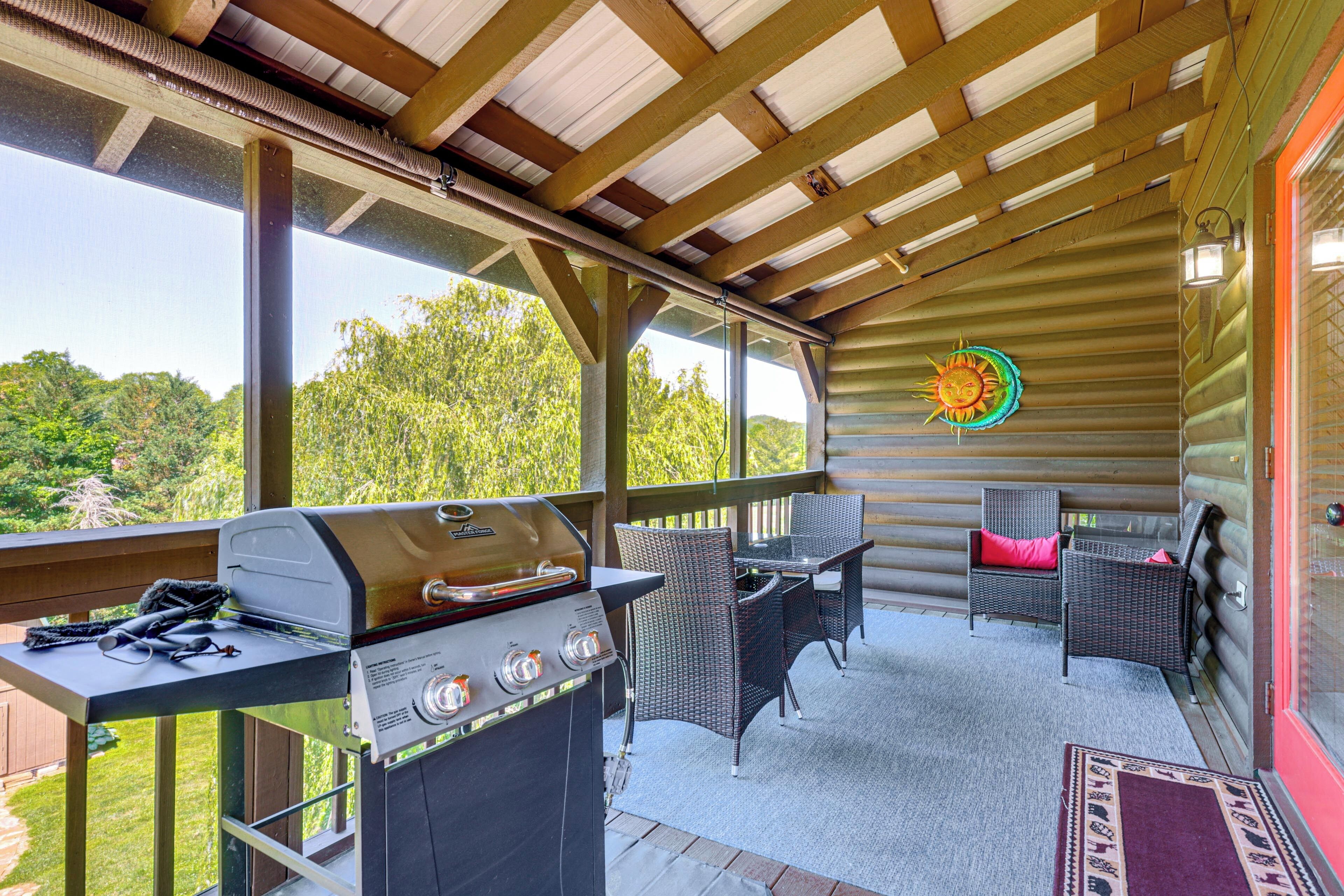 An outdoor patio with a grill, wicker furniture, and a view of the forest.