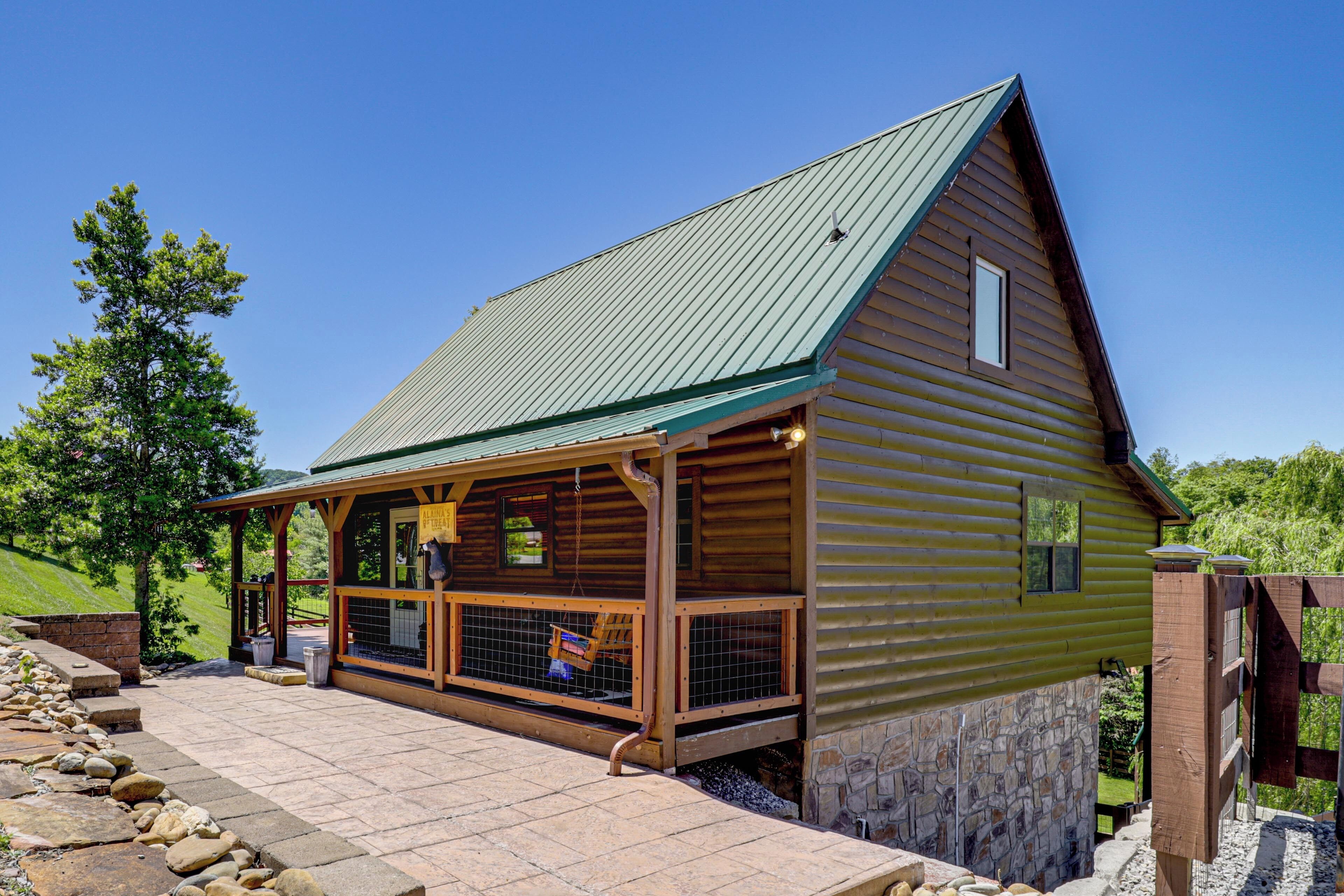 A log cabin with a covered porch, stone foundation, and a metal roof.