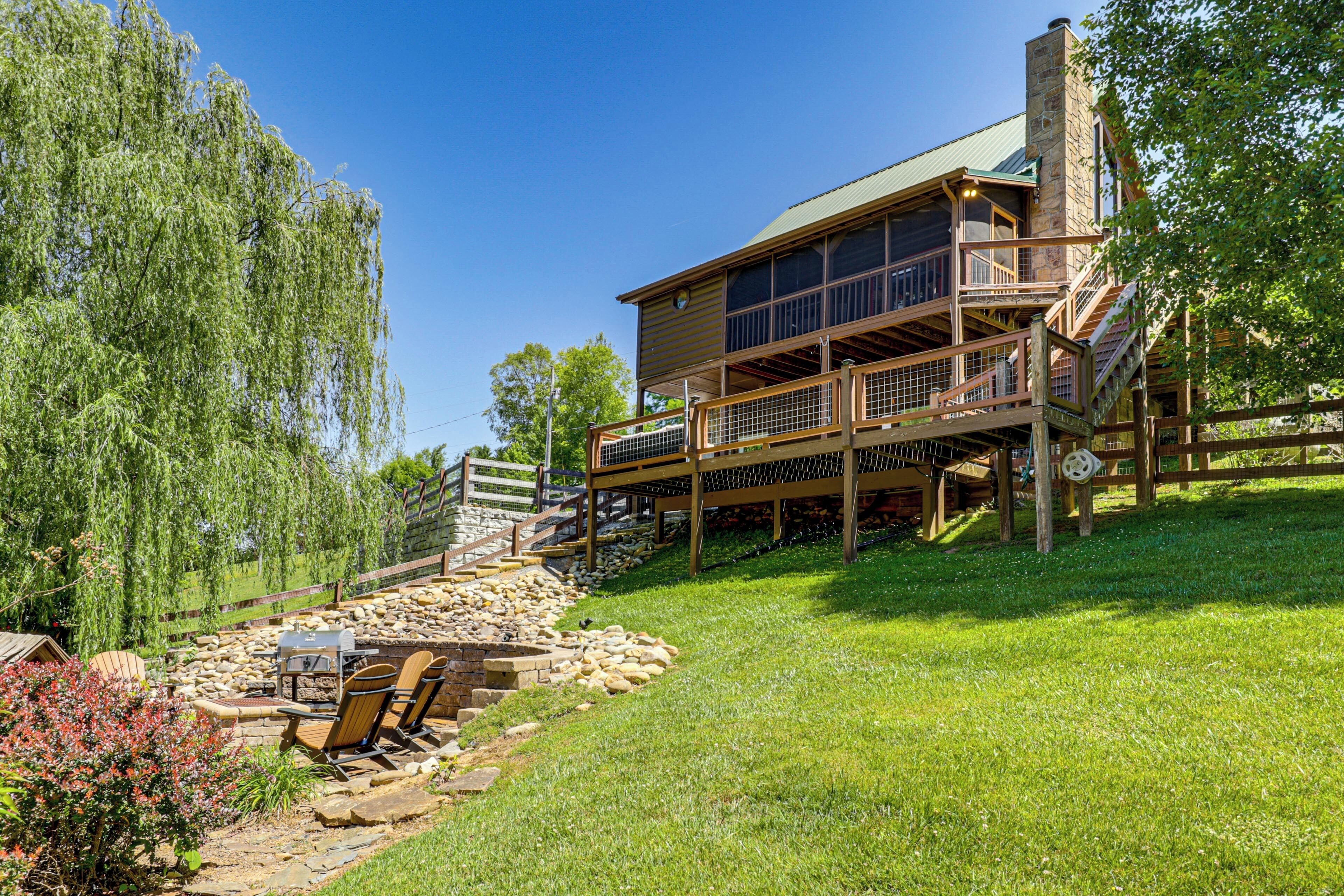 A two-story wooden house with a deck, stone steps, and a barbecue area.