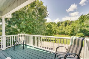 A covered porch with two striped chairs and a bench, overlooking a green landscape with trees and a road. - Pigeon Forge Home w/ Deck & Hot Tub Near Town! (Pigeon Forge)