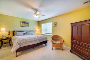 A bedroom with a bed, a ceiling fan, a window with blinds, a wicker chair, and a wooden dresser. - Pigeon Forge Home w/ Deck & Hot Tub Near Town! (Pigeon Forge)