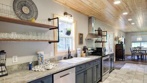 Une cuisine moderne avec des meubles de couleur sombre, un plan de travail en marbre et une grande fenêtre.