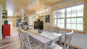 Une cuisine spacieuse avec des meubles en bois, une table à manger avec des chaises et une grande fenêtre offrant une vue sur l’extérieur.