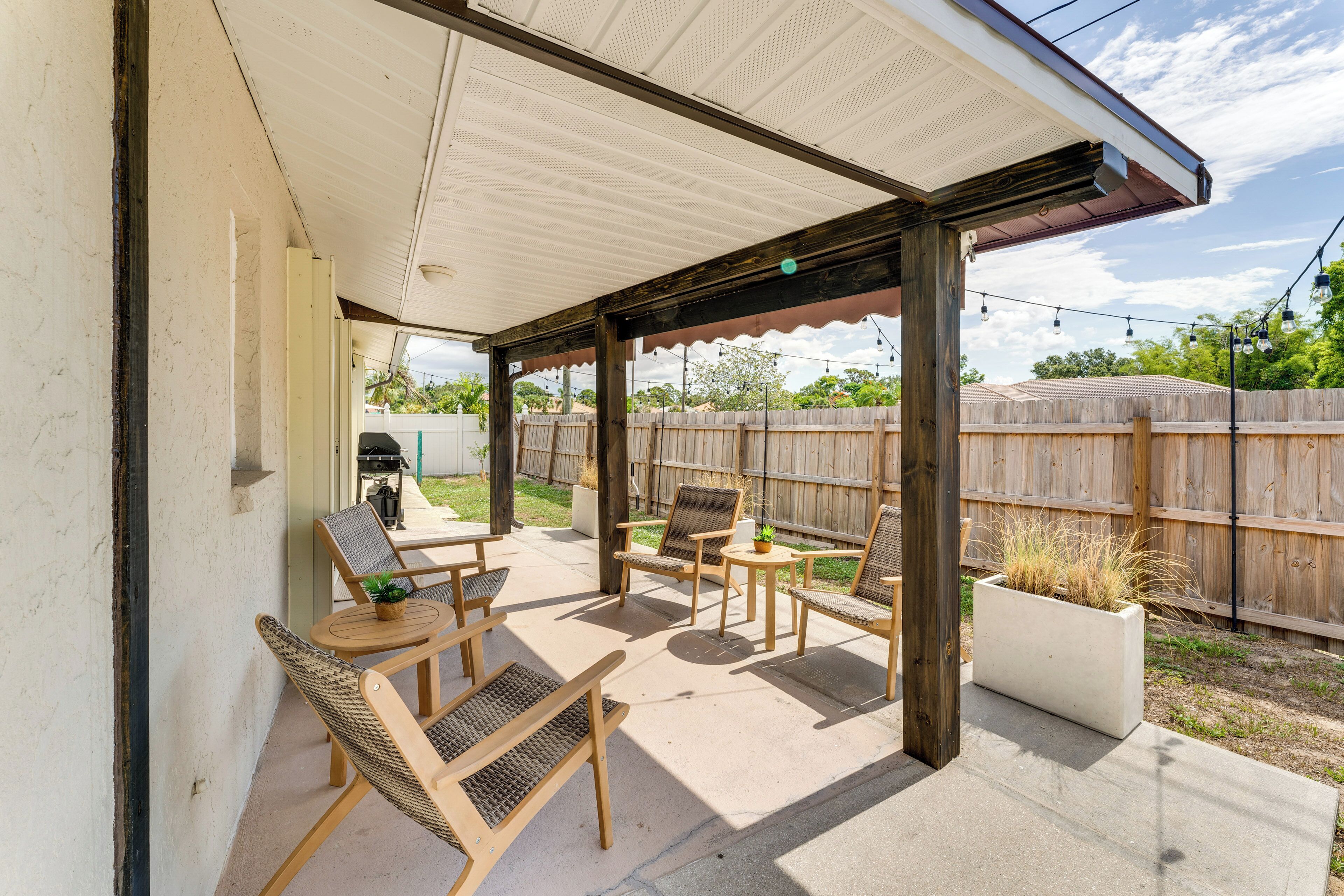 An outdoor patio with wooden furniture, a covered seating area, and a concrete floor.