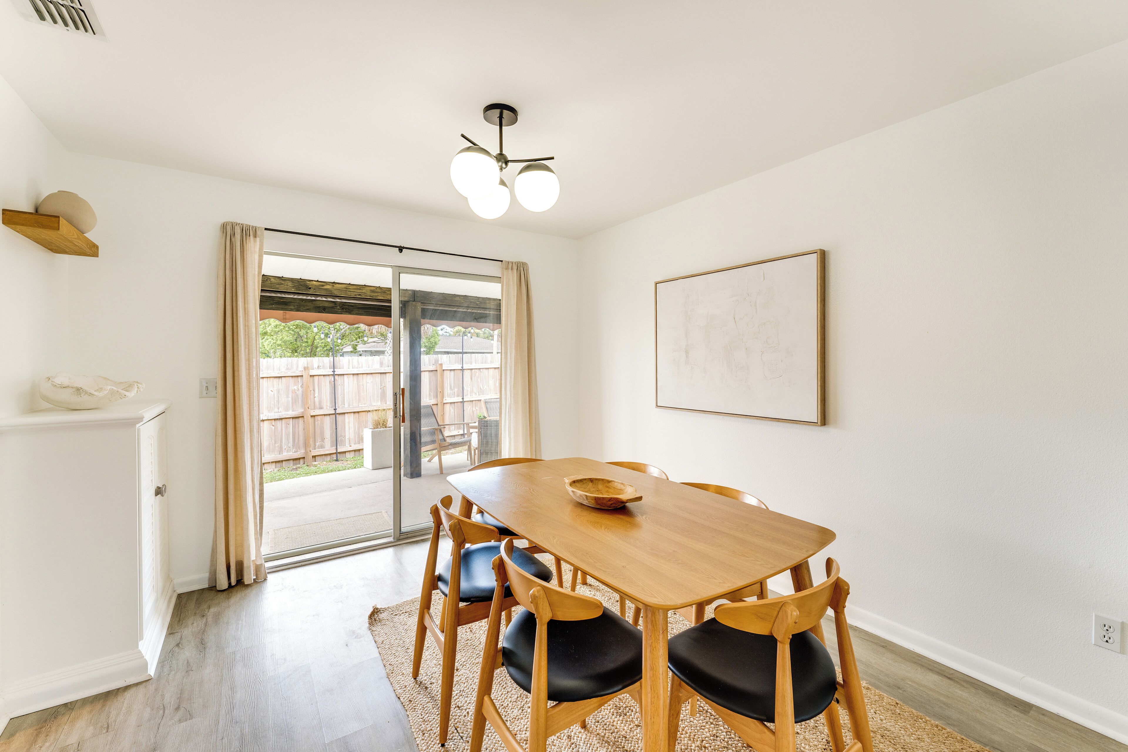 A dining area with a wooden table and chairs, a ceiling fan, and a sliding glass door leading to an outdoor space.