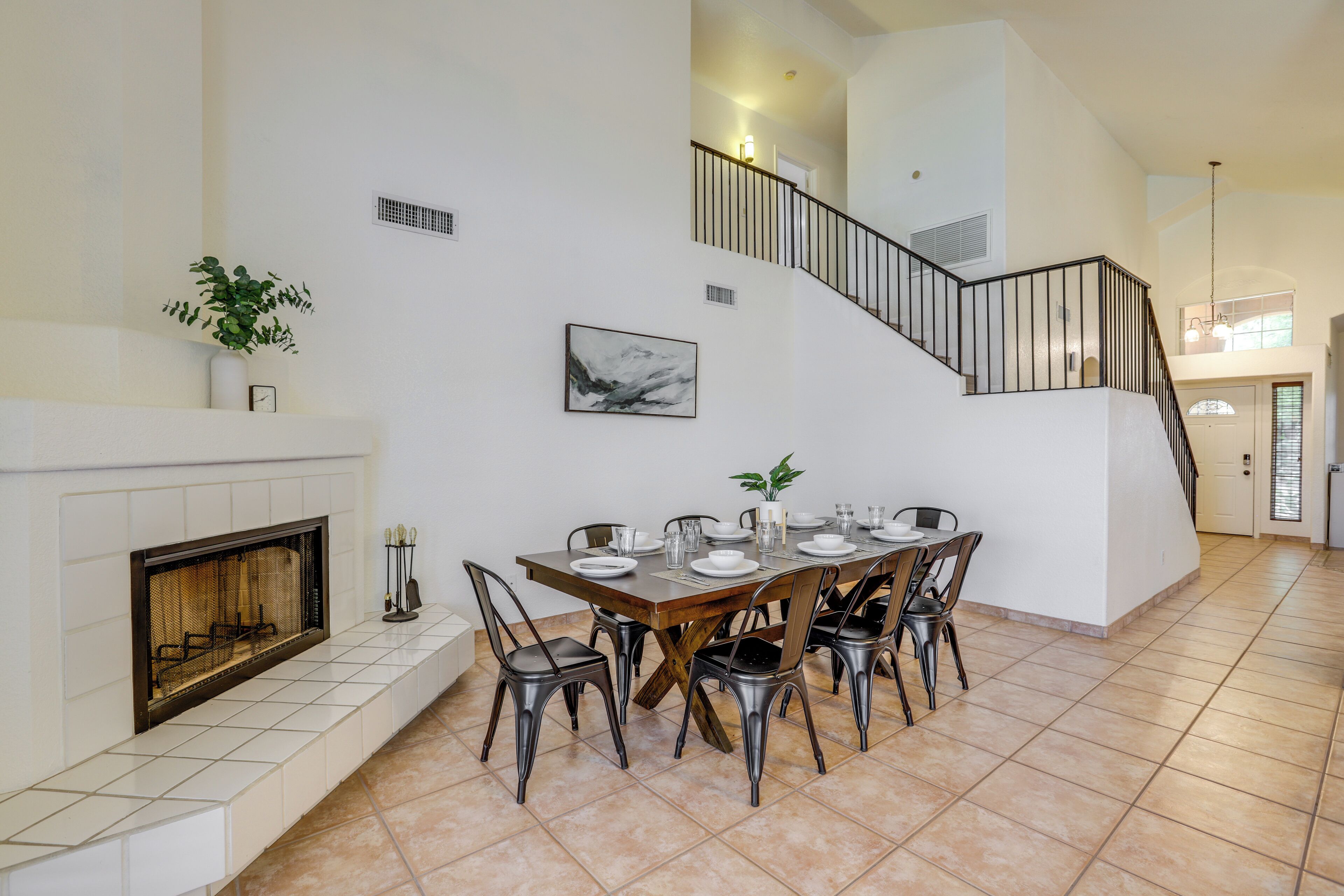 A spacious dining area with a fireplace, a staircase, and a view to the upper level.