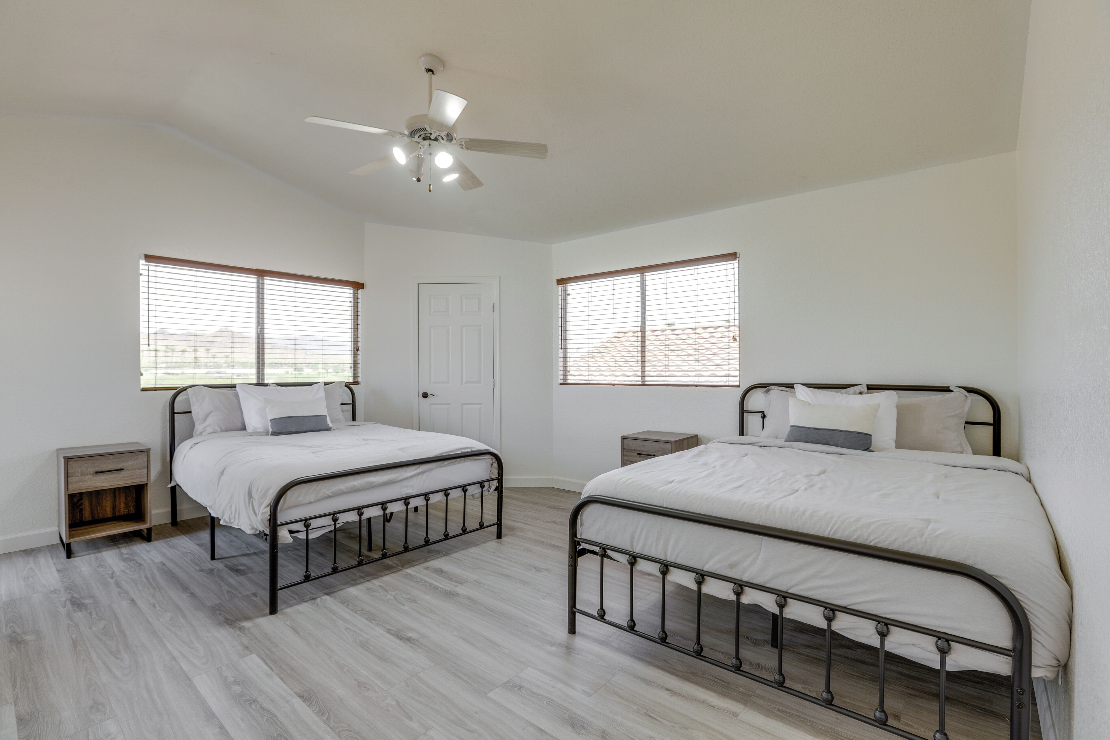 A bedroom with two single beds, a ceiling fan, and a door.