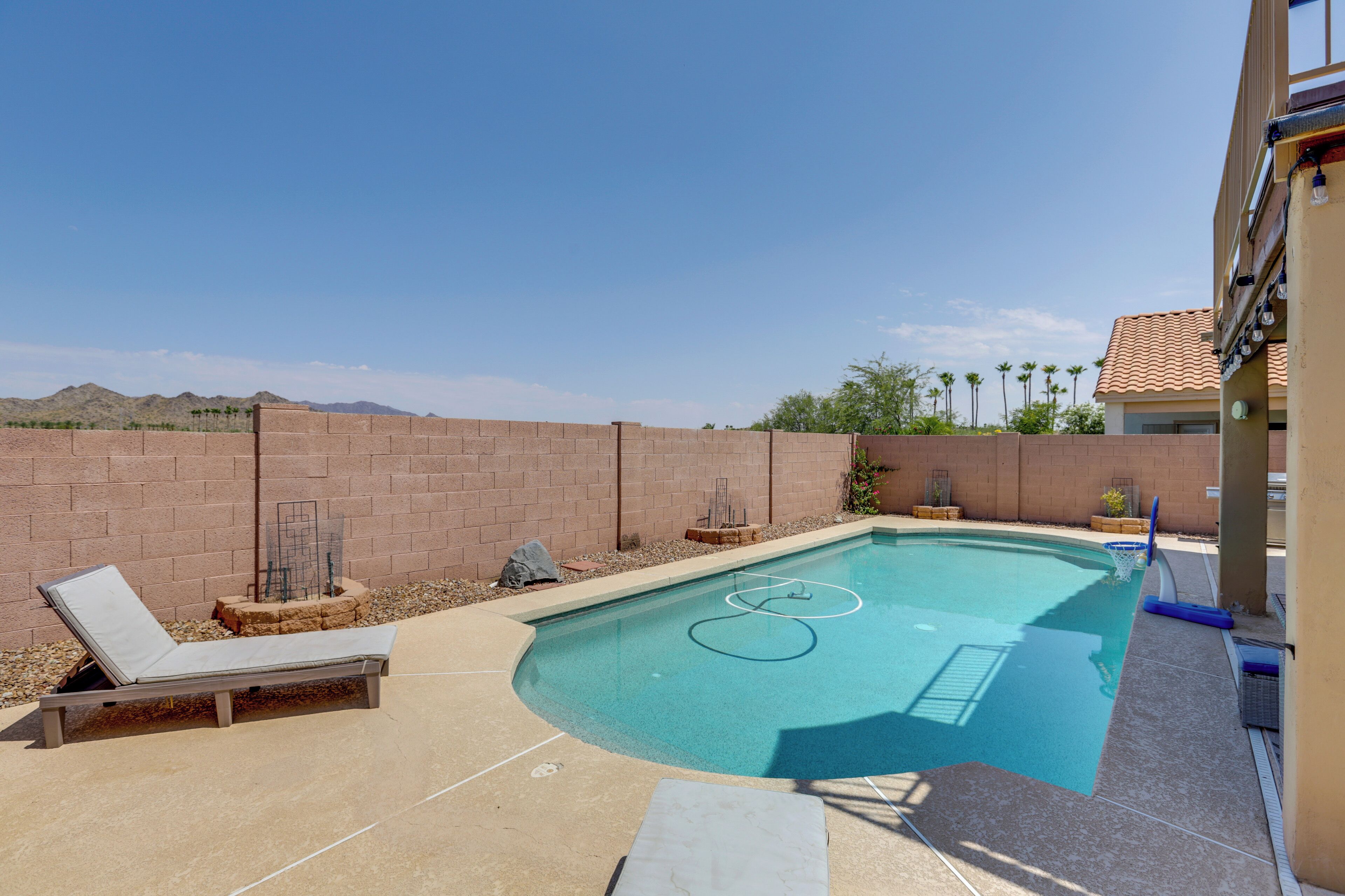 A swimming pool with lounge chairs, a brick wall, and a view of distant mountains.