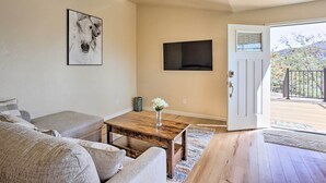 A living room with a sofa, a coffee table, a TV mounted on the wall, and a door leading to an outdoor area. - Oakhurst Duplex ~ 13 Mi to Yosemite National Park! (Oakhurst)