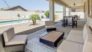 A covered outdoor patio with seating, a pool, and a view of neighboring houses.