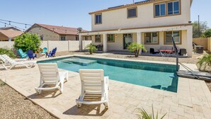 A two-story house with a swimming pool, outdoor seating, and a barbecue area.