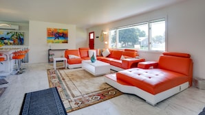 En moderne stue med en hvid og orange sofasæt, et sofabord og et farverigt tæppe.