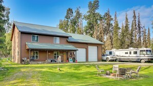Ein zweigeschossiges Haus mit Garage und überdachter Veranda, vor der ein großes Wohnmobil steht.