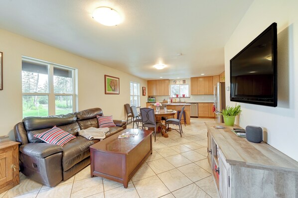 A spacious living room with a leather sofa, a wooden coffee table, and a flat-screen TV mounted on the wall.