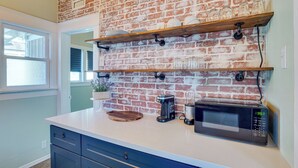 A kitchen with a brick wall, wooden shelves, a coffee maker, and a microwave. - 1 Mi to Dtwn! Bright Long Beach Apartment (Long Beach)