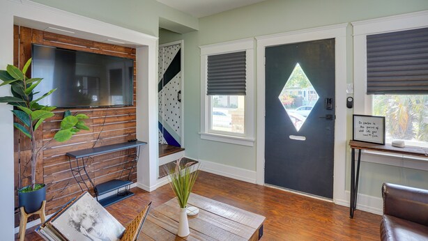 A modern living room with a wooden floor, a black door, and a large window. - 1 Mi to Dtwn! Bright Long Beach Apartment (Long Beach)