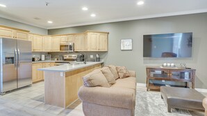 A modern kitchen with wooden cabinets, a stainless steel refrigerator, and a built-in island. - Luxe Midway Condo w/ Golf Course & Mountain Views! (Midway)