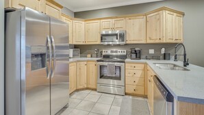 A modern kitchen with stainless steel appliances, wooden cabinets, and a granite countertop. - Luxe Midway Condo w/ Golf Course & Mountain Views! (Midway)