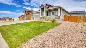 A residential house with a well-maintained lawn, a wooden fence, and a clear sky. - Stunning Peyton Retreat w/ Game Room, Private Yard (Peyton)