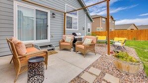 A covered patio with wicker furniture, a grill, and a wooden fence. - Stunning Peyton Retreat w/ Game Room, Private Yard (Peyton)