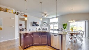 A modern kitchen with dark wooden cabinets, a granite countertop, and a built-in dishwasher. - Stunning Peyton Retreat w/ Game Room, Private Yard (Peyton)