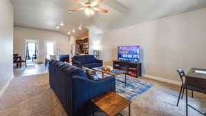 A spacious living room with a dark blue sofa, a wooden coffee table, and a flat-screen TV. - Pet-friendly Lubbock Home - 10 Mi to Downtown (Lubbock)