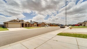 A suburban street with houses, a clear sky, and a few vehicles. - Pet-friendly Lubbock Home - 10 Mi to Downtown (Lubbock)