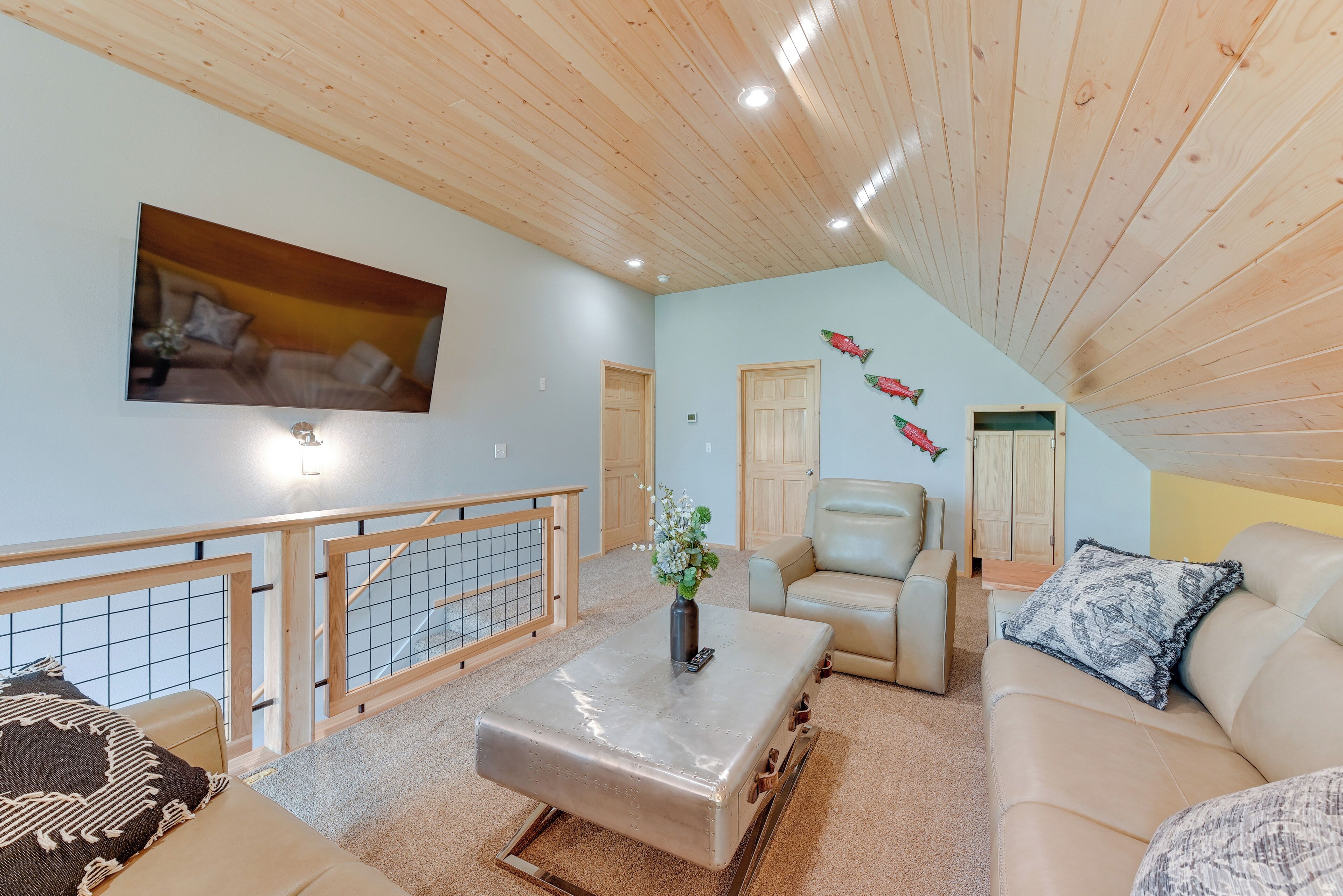 Ein geräumiges Wohnzimmer mit hohen Decken, einem großen Gemälde, einem Couchtisch mit einer Vase und einem Sofa mit einem gemusterten Kissen.