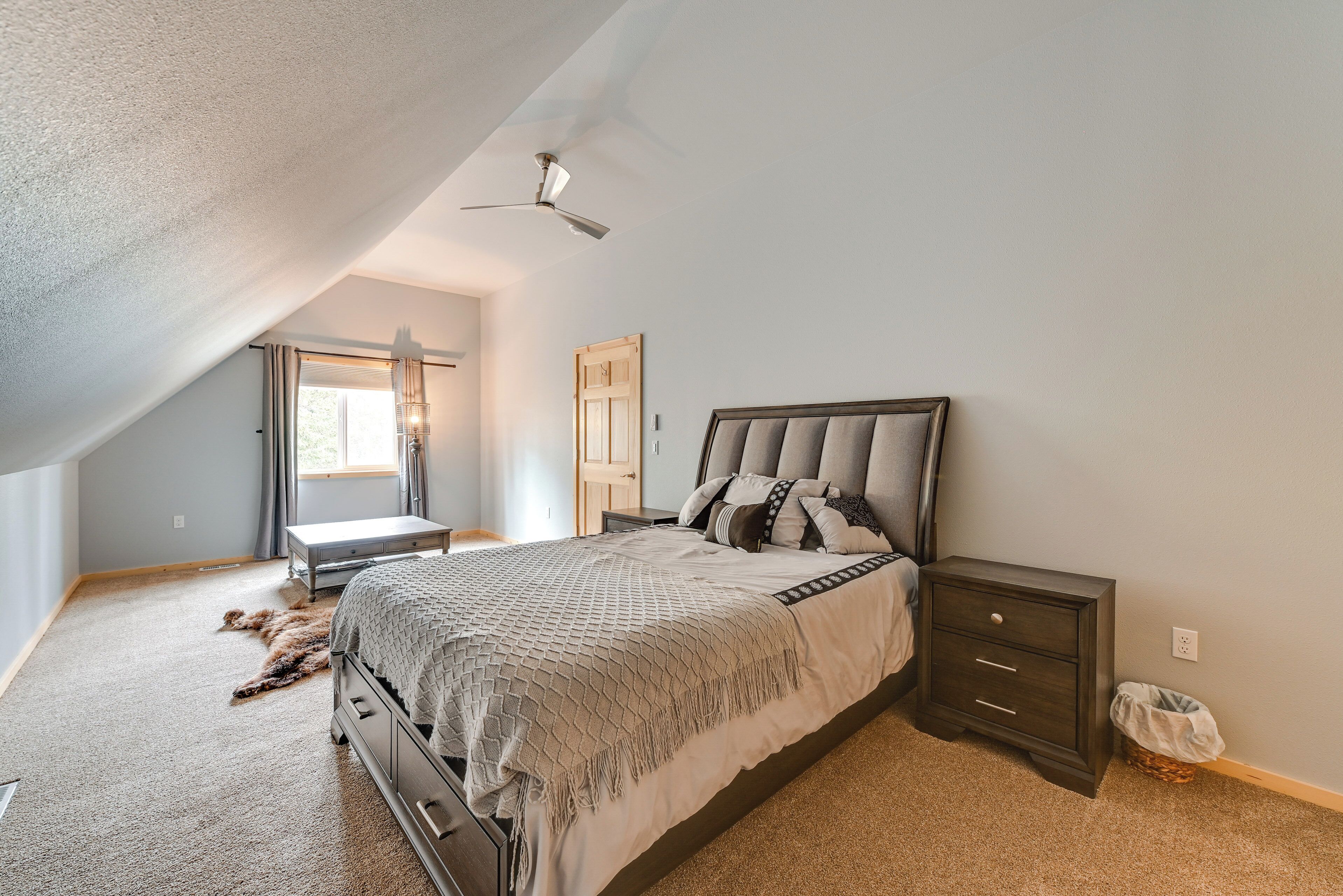 A bedroom with a bed, nightstand, dresser, and a ceiling fan.