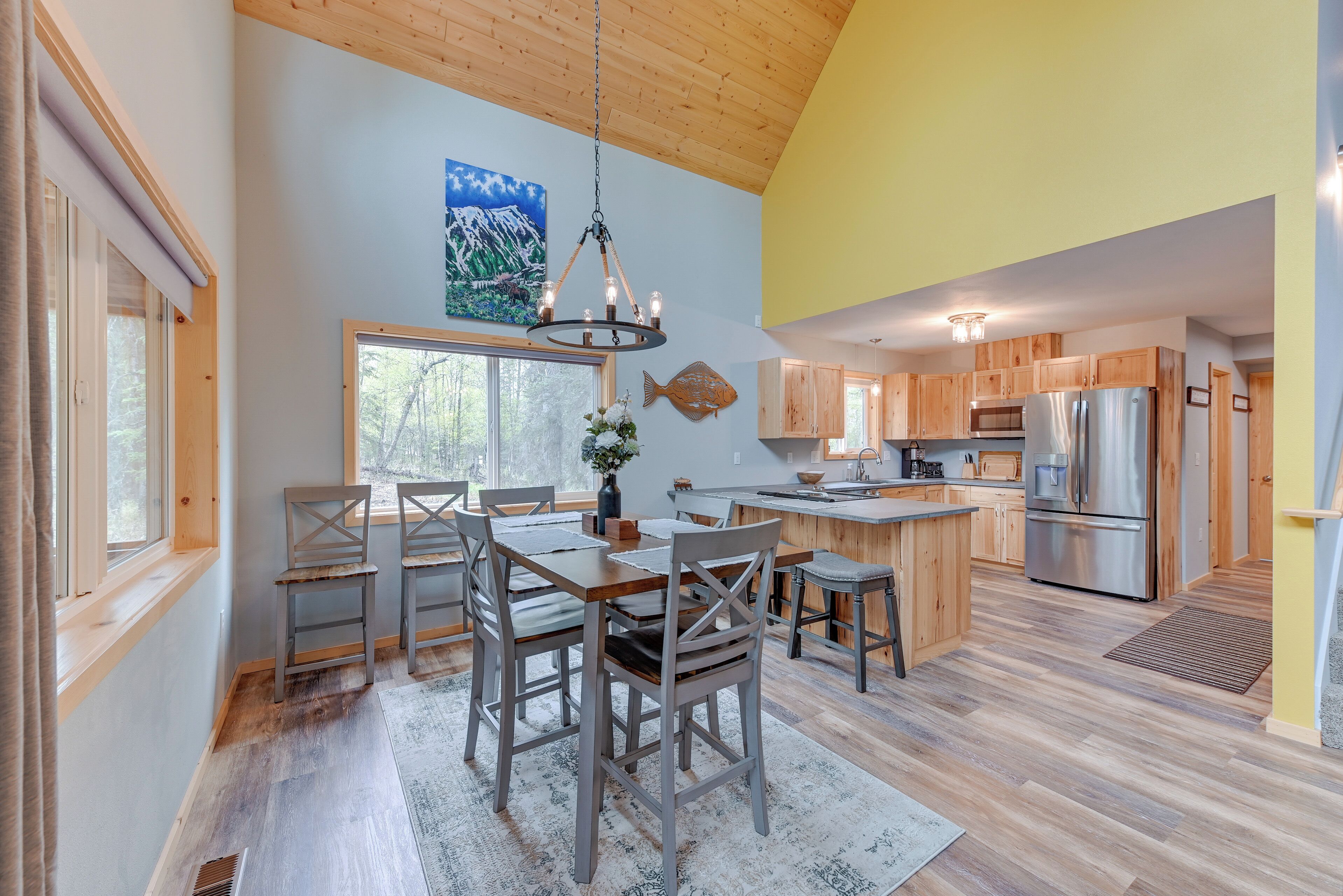 A spacious kitchen with wooden cabinets, a stainless steel refrigerator, and a dining area with a wooden table and chairs.