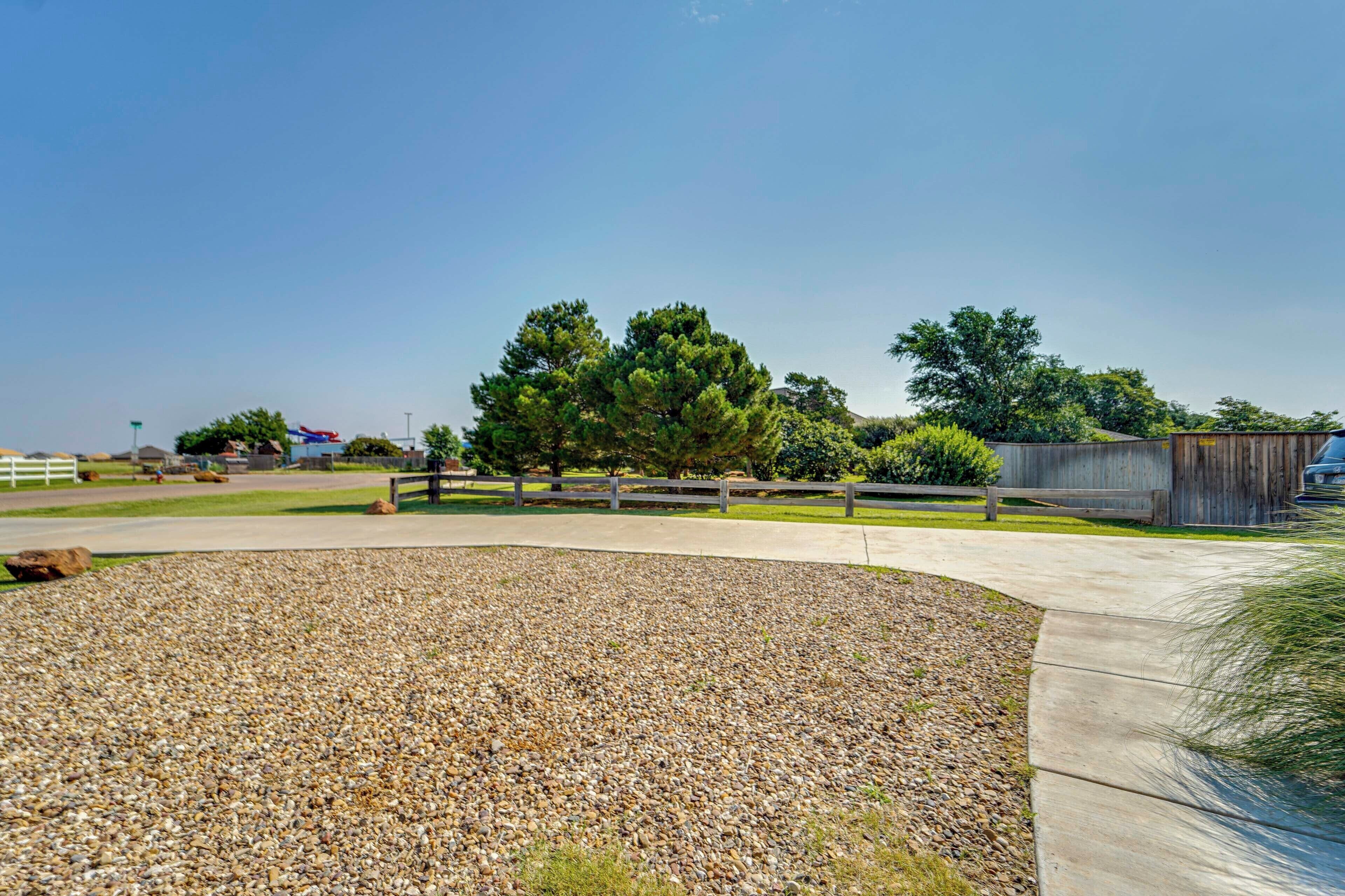 A landscaped area with a gravel path, wooden fence, and trees.