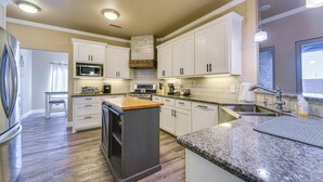 A modern kitchen with white cabinets, a granite countertop, and a built-in oven. - Spacious Lubbock Home w/ Private Pool & Yard! (Lubbock)