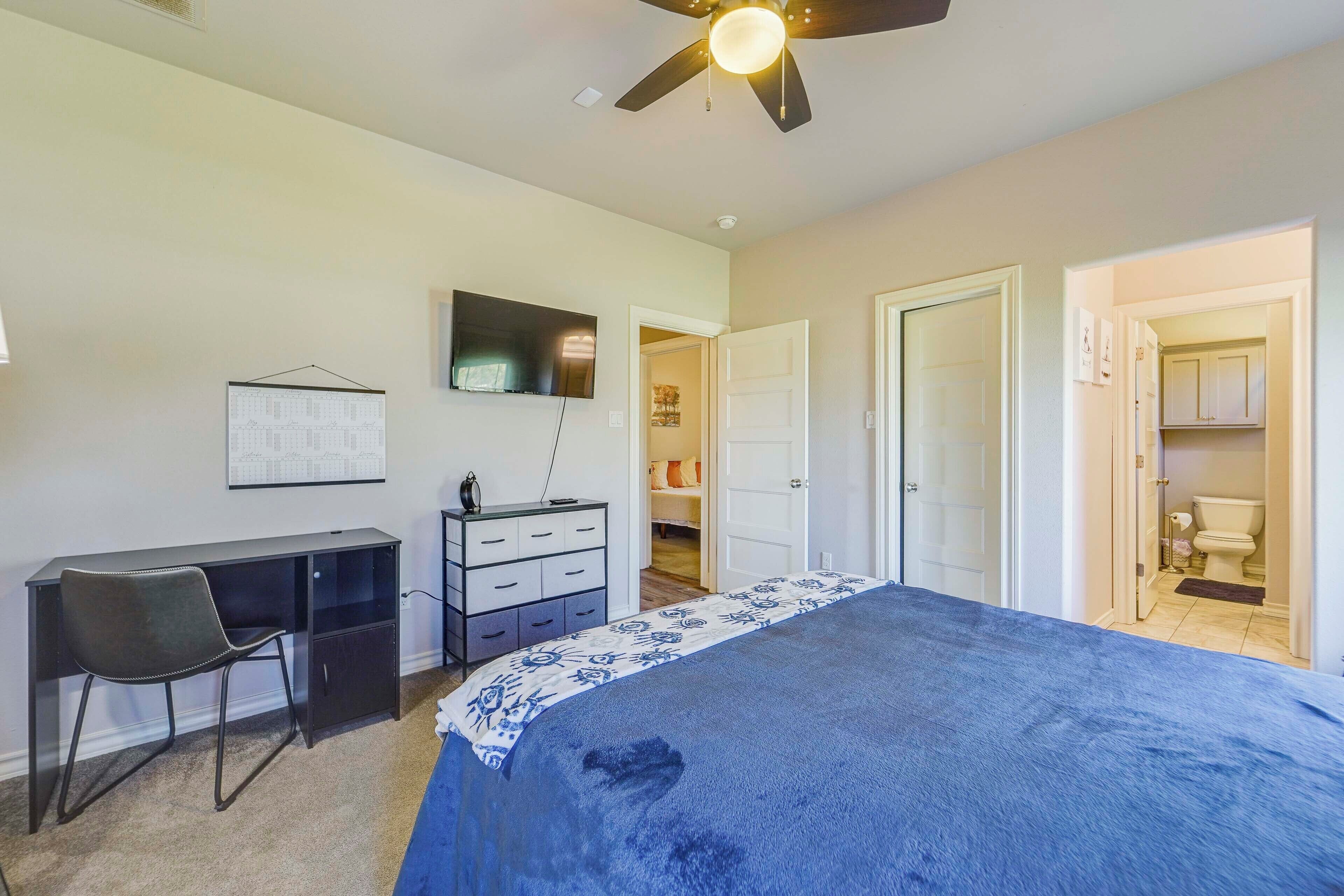 A bedroom with a bed, desk, chair, wardrobe, and a ceiling fan.