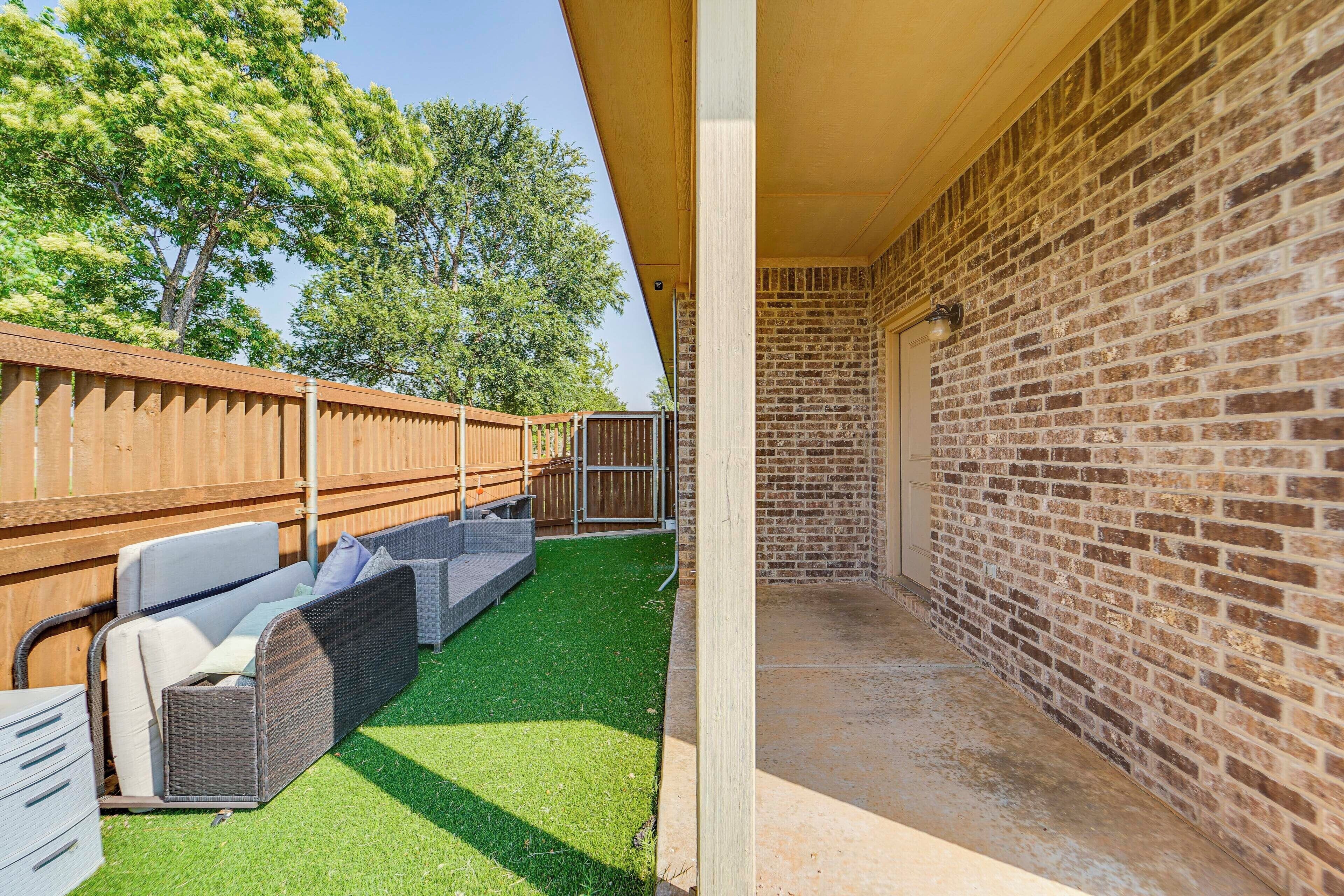 A patio area with a brick wall, a wooden fence, and outdoor furniture.